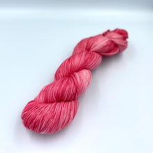 Load image into Gallery viewer, Skein of superwash merino yarn hand dyed in a strawberry pink color
