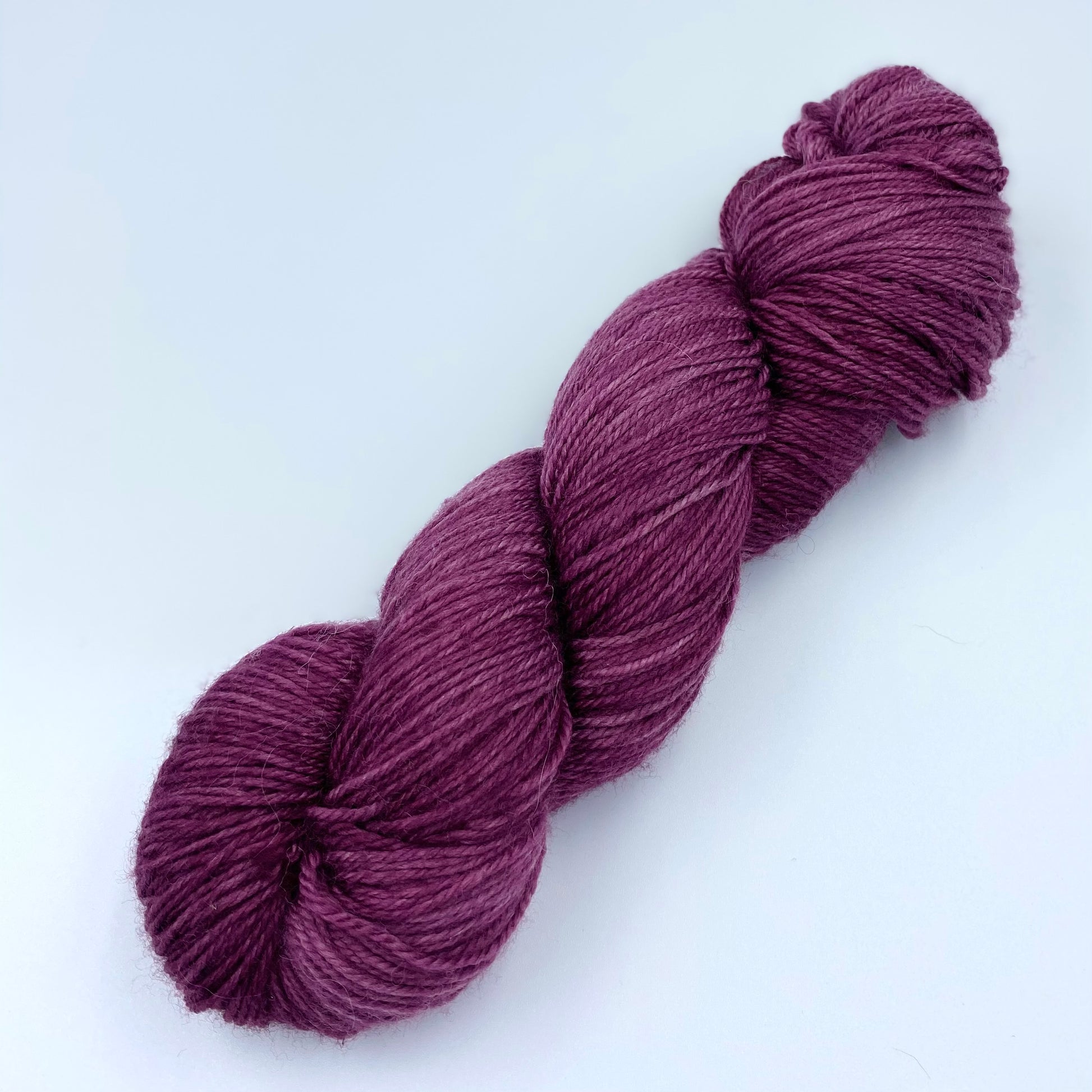 A skein of sparkly wool and nylon yarn hand dyed in the color deep mauve