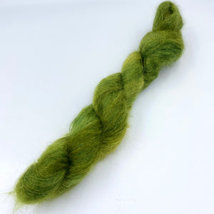 A skein of hand dyed kid mohair and silk yarn in an army green  color 