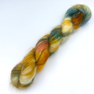 A skein of hand dyed kid mohair and silk yarn in a  mix of orange, blue and yellow  color 