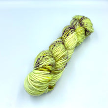 Load image into Gallery viewer, Skein of superwash merino yarn hand dyed in a soft yellow with purple specklecolor
