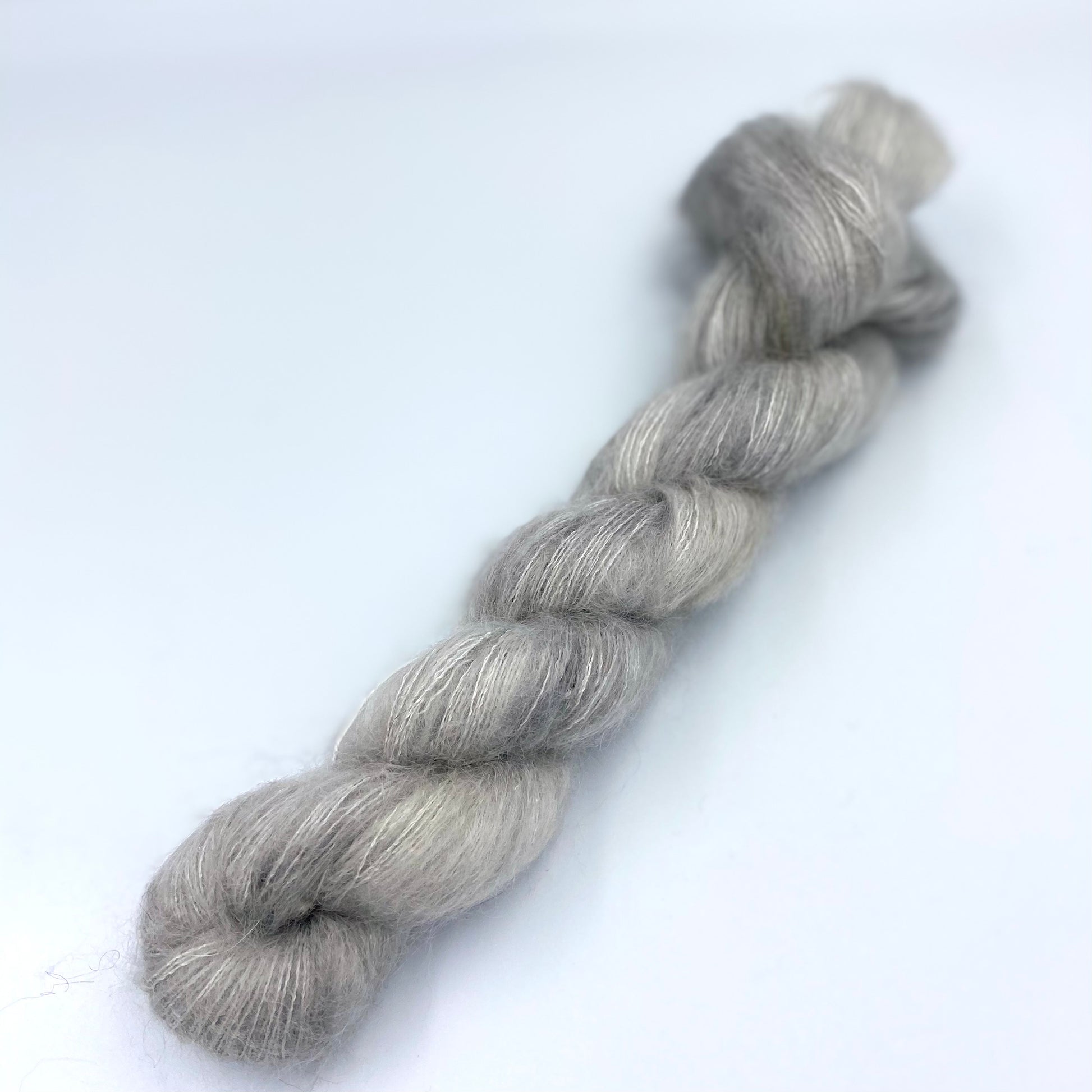 A skein of hand dyed kid mohair and silk yarn in a silver color 