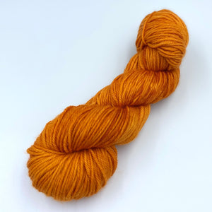 Skein of superwash merino yarn hand dyed in an orange color