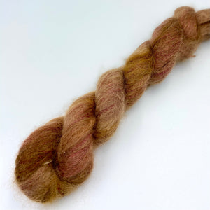 A skein of hand dyed kid mohair and silk yarn in a reddish brown  color 