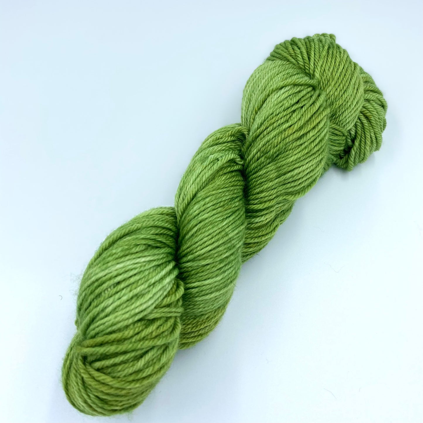 Skein of superwash merino yarn hand dyed in an army green color