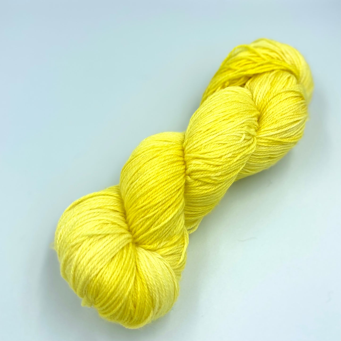 A skein of sparkly wool and nylon yarn hand dyed in the color yellow