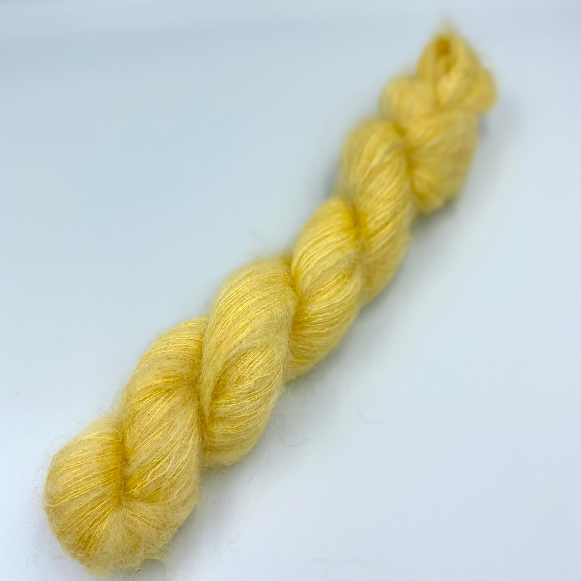 A skein of hand dyed kid mohair and silk yarn in a  soft yellow  color 